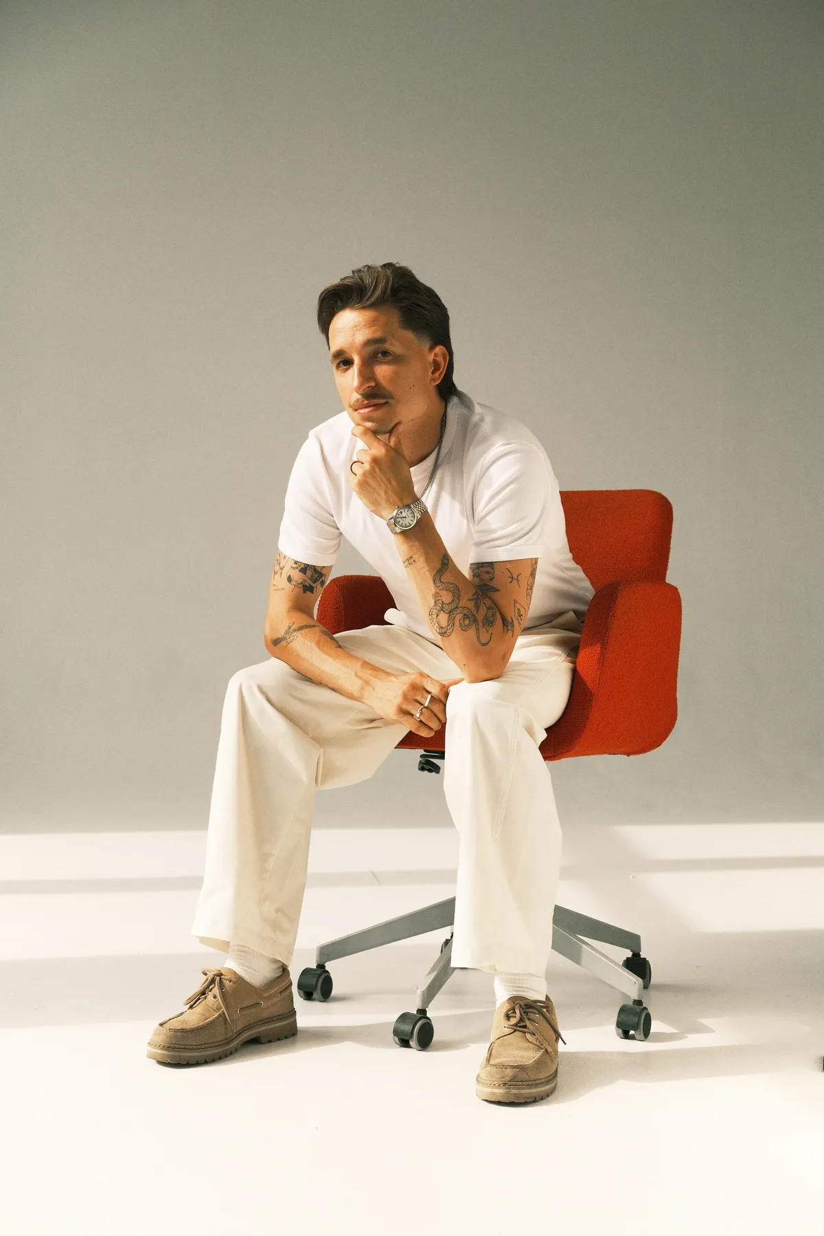 Ernestas sitting on a red chair in a minimalist studio